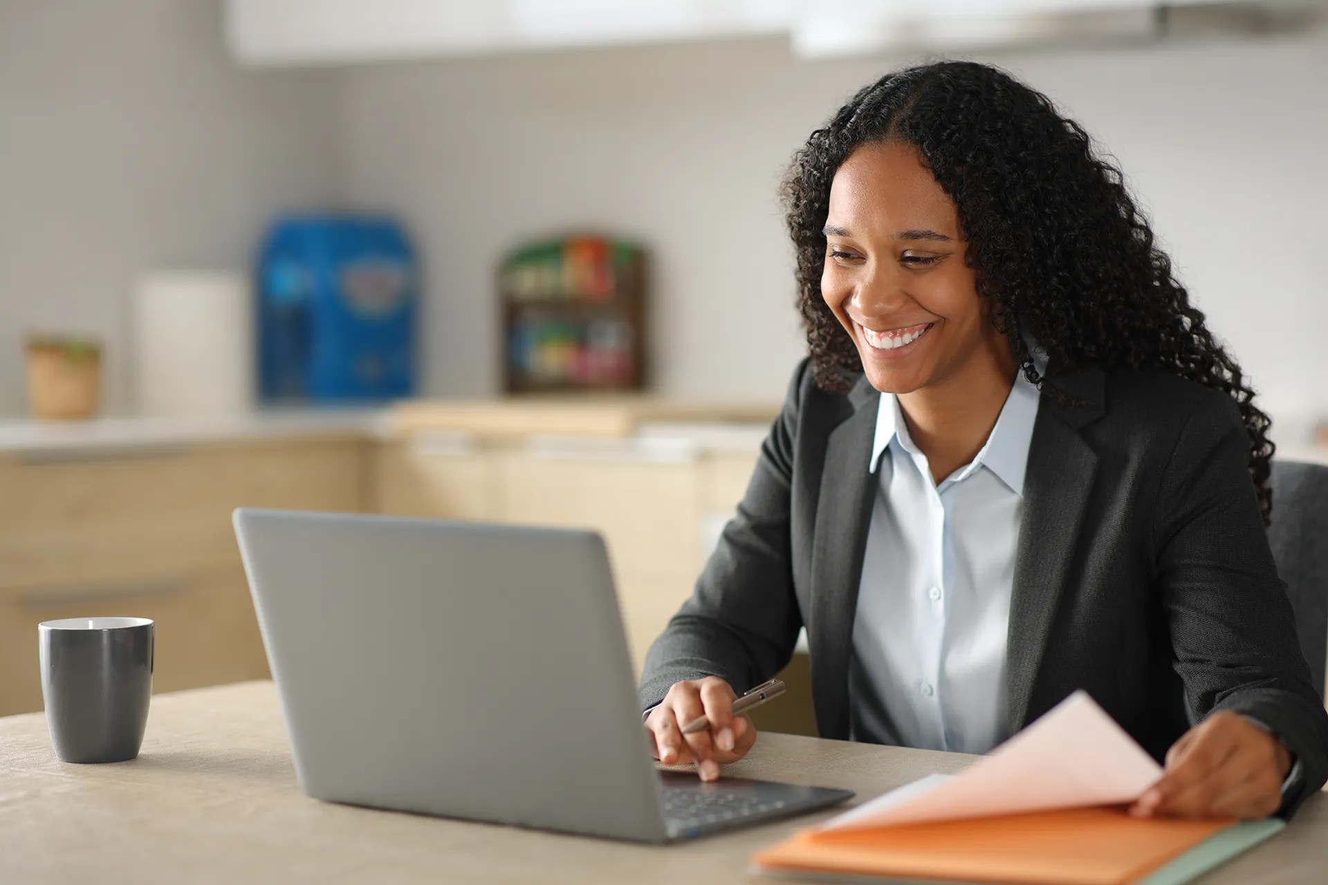 A professional seated at a desk uses a laptop while reviewing paperwork, demonstrating virtual collaboration, planning, or administrative work.