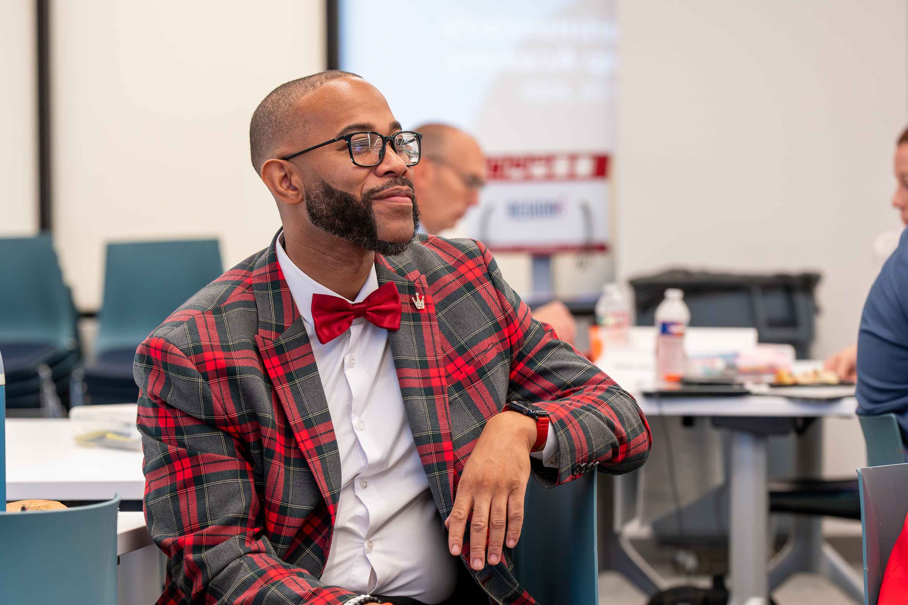 Man with glasses, a plaid jacket, and a red bow tie speaking during a Region 4 training session.